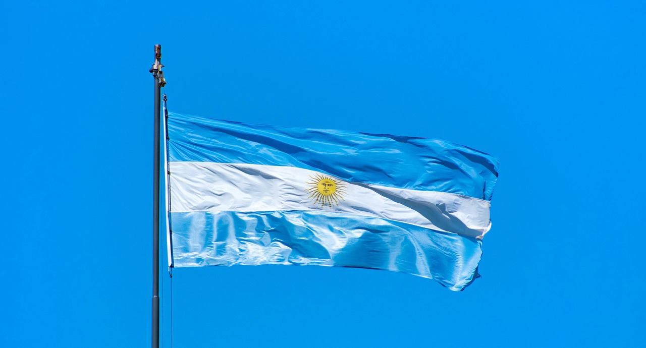 Argentina's flag waving against a clear blue sky.