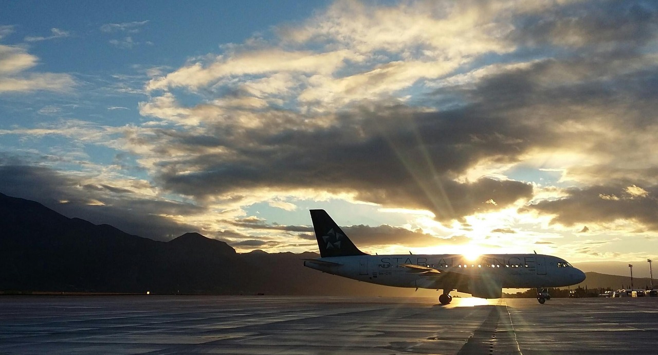 A plane on the tarmac with the sun setting behind it, casting a warm glow over the scene.