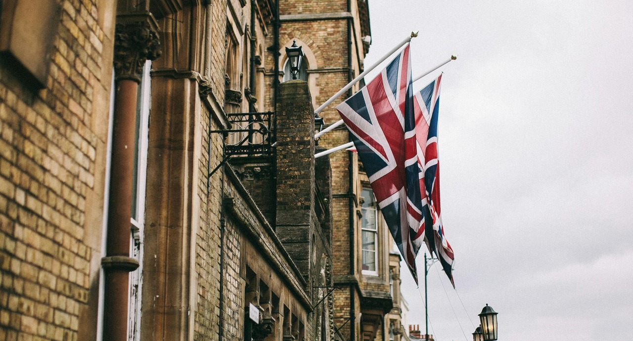 The image shows a building with Union Jack flags hanging from it, symbolizing travel and British heritage.