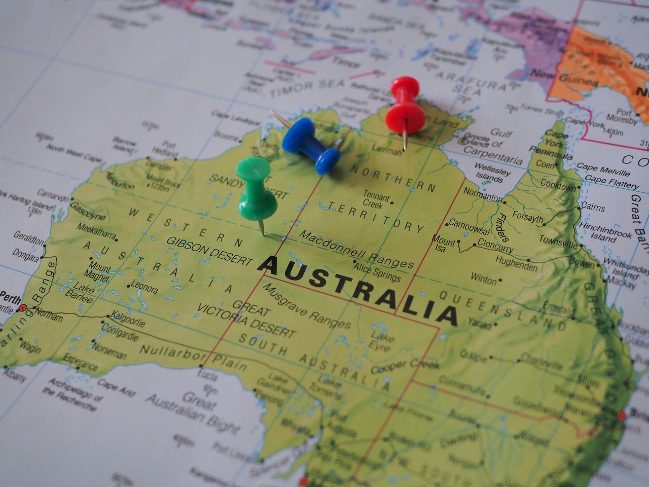 Close-up of a map of Australia with colored push pins marking locations in Western Australia, Northern Territory, and Queensland, highlighting regional points of interest or travel routes.
